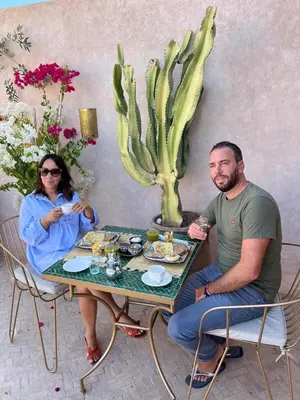 a man and woman sitting at a table with food at Riad Darchica in Marrakech