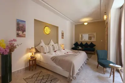 a bedroom with a large bed and a blue chair at Riad Darchica in Marrakech