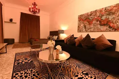 a living room with a black couch and a table at Riad avec piscine - Wifi- petit déjeuner - Bon Emplacement in Marrakech
