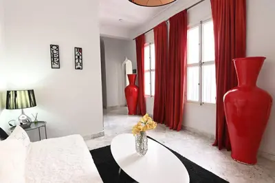a living room with two red vases and a table at Riad avec piscine - Wifi- petit déjeuner - Bon Emplacement in Marrakech
