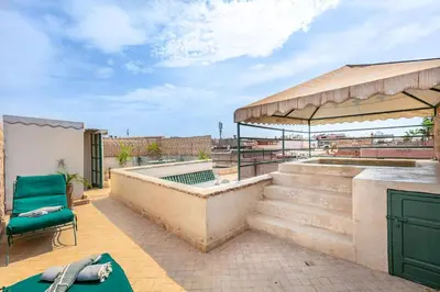 a patio with a pool and a green chair at Charming riad in the medina of Marrakech with 4 nice rooms in Marrakech