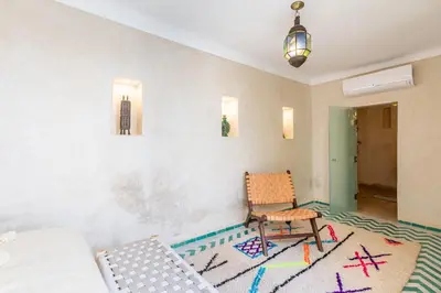 a living room with a chair and a table at Riad Itri (إتري) Exclusif - Marrocan Breakfast in Marrakech