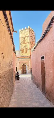 an alley with a large clock tower in the distance at Dar Kamilya in Marrakech
