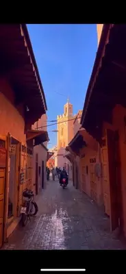 a narrow street with a building with a clock tower at Dar Kamilya in Marrakech