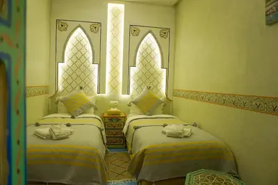 two beds in a room with two windows at Flowers riad in Marrakech
