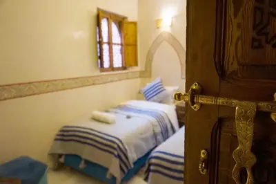 a bedroom with two beds with blue and white sheets at Flowers riad in Marrakech