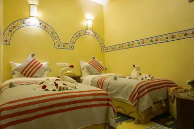 two beds in a room with two swans on them at Flowers riad in Marrakech