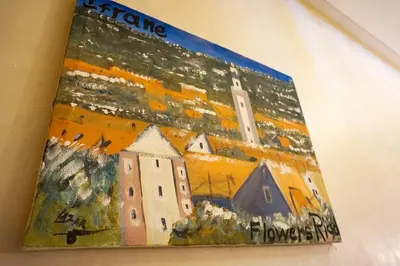 a book with a painting of a town at Flowers riad in Marrakech