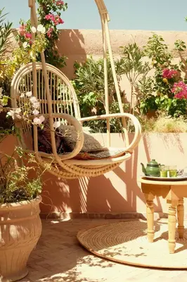 a wicker chair sitting on a patio with flowers at Riad BE Marrakech in Marrakech