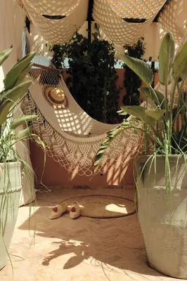 a hammock with a snake laying on the ground next to two plants at Riad BE Marrakech in Marrakech