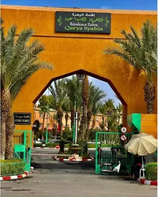 an entrance to a building with palm trees and a sign at Quarya Assiyahia - Riad CAMILIA- Maison entière avec piscine in Marrakech