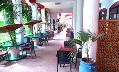a restaurant with tables and chairs and plants in it at Quarya Assiyahia - Riad CAMILIA- Maison entière avec piscine in Marrakech