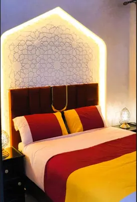 a bedroom with a large bed with a large headboard at Quarya Assiyahia - Riad CAMILIA- Maison entière avec piscine in Marrakech