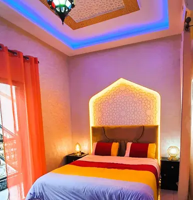 a bedroom with a bed with a colorful wall at Quarya Assiyahia - Riad CAMILIA- Maison entière avec piscine in Marrakech