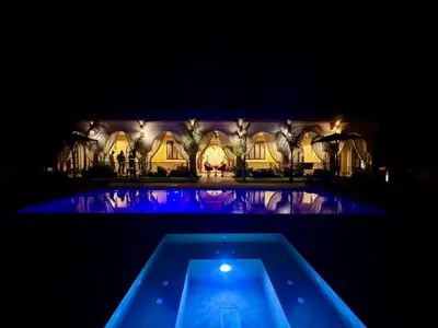 a swimming pool in front of a house at night at Riad Safran Ralya in Marrakech