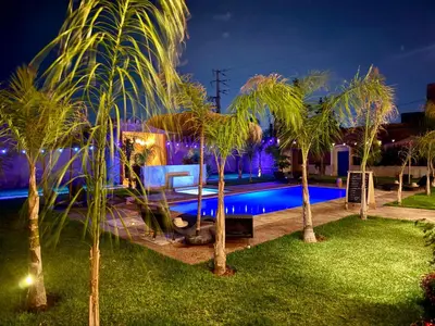 a pool at night with palm trees around it at Riad Safran Ralya in Marrakech