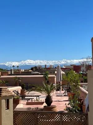 a balcony with tables and chairs and a view of the mountains at Riad Jnan El Cadi in Marrakech