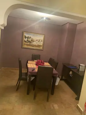 a dining room table with chairs and a painting on the wall at Appartement Ensoleillé vue Piscine in Marrakech