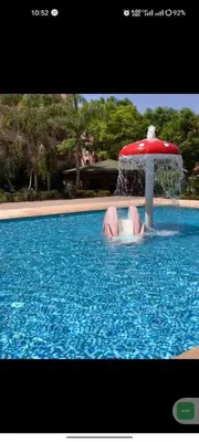 a person in a swimming pool with a fountain at Appartement Ensoleillé vue Piscine in Marrakech