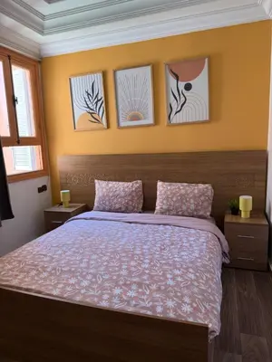 a bedroom with a bed with four pictures on the wall at Julie's AIRPORT Apartment in Marrakech