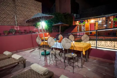 a table with chairs and an umbrella on a balcony at Riad Dar Jdati in Marrakech