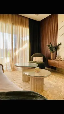 a living room with two tables and a chair at Luxueux Appartement Prestigia in Marrakech