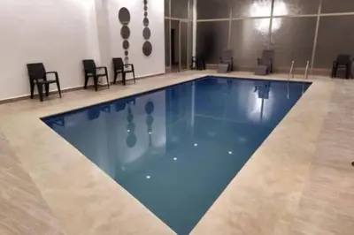 a large swimming pool in a room with chairs at Chic & Cosy au coeur d’hivernage in Marrakech