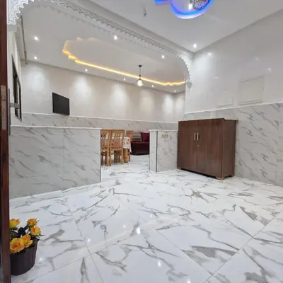 a lobby with white marble flooring and a room with chairs at Bel appartement de 2 chambres M in Marrakech