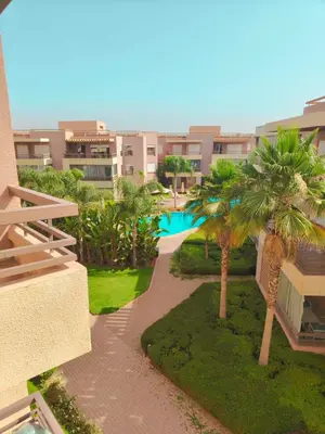 an apartment building with a swimming pool and palm trees at LUXURY APPART Pool view Riad Garden in Marrakech