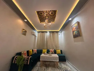 a living room with a couch and a chandelier at Charmant Appartement 2 Chambres pour Sejours en Famille Marrakech in Marrakech