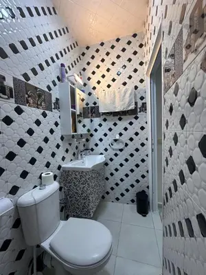 a bathroom with a toilet and a black and white tile wall at Charmant Appartement 2 Chambres pour Sejours en Famille Marrakech in Marrakech