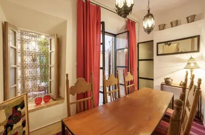 a dining room with a wooden table and a window at Riad Slima - riad privatisé -Marrakech au coeur de la médina 1 Acheminement compris Aéroport riad in Marrakech