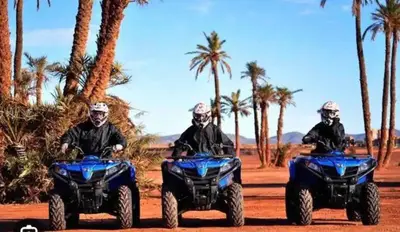 three people riding atvs on a dirt road with palm trees at Chez Alex in Marrakech