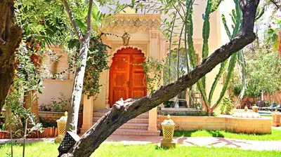 a tree branch in front of a house with a red door at Barthélemy Guest House in Marrakech