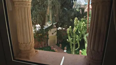a view of a garden from a window with columns at Barthélemy Guest House in Marrakech