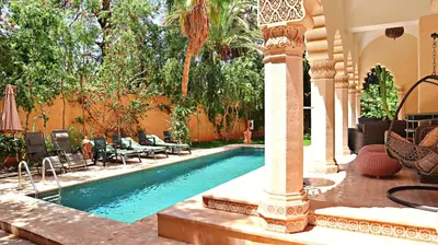 a swimming pool in a yard with a pillar at Barthélemy Guest House in Marrakech