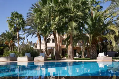 a hotel with palm trees and a swimming pool at Maggy Rose in Marrakech