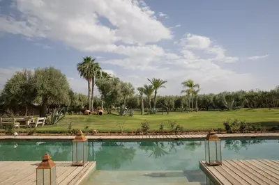 a swimming pool with palm trees and a golf course at Villa MISH-MISH in Marrakech