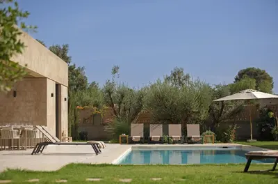a swimming pool with chairs and an umbrella at Villa PEPE in Marrakech