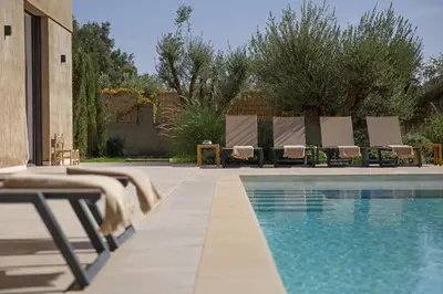 a swimming pool with chairs and a table next to it at Villa PEPE in Marrakech
