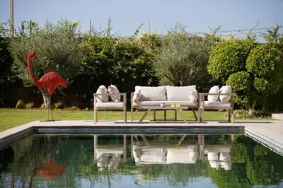 two chairs and a red bird statue next to a pool at ADA ADA modern villa with heated private pool next city center in Marrakech