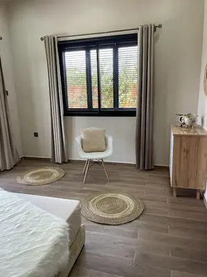 a bedroom with a bed and a chair and a window at Villa Amèle,calme,Ensoleillé,Piscine,Salle de jeux in Marrakech
