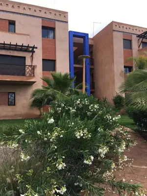 a building with a tree in front of it at Appartement paisible et abordable Palmeraie Marrakech in Dar Caïd Layadi