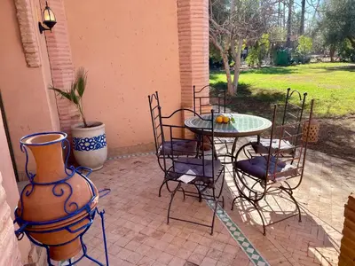 a patio with a table and chairs and a vase at Au Temps Des Fleurs - Marrakech in Marrakech