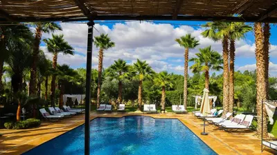 a pool with lounge chairs and palm trees at Luxury heated pool Villa Marrakech in Marrakech