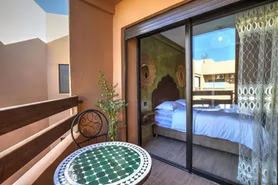 a room with a balcony with a bed and a table at Nour 5 el bellar in Marrakech