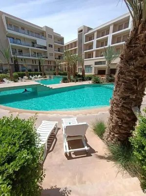 a swimming pool with lounge chairs in front of a building at appartement en résidence in Marrakech