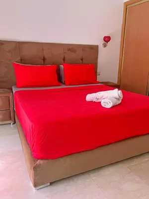 a red bed with red pillows and a towel on it at appartement génial in Marrakech