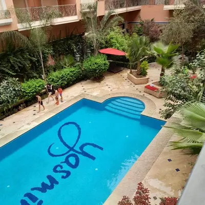 a swimming pool in a resort with people standing around it at appartement génial in Marrakech