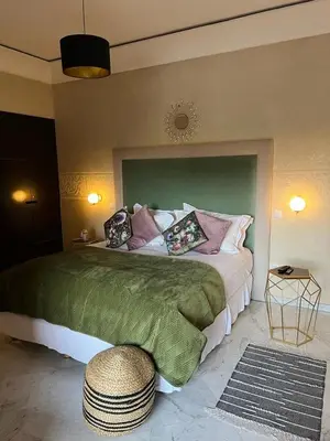 a bedroom with a large bed with a green headboard at Appartement Hivernage M Avenue in Marrakech